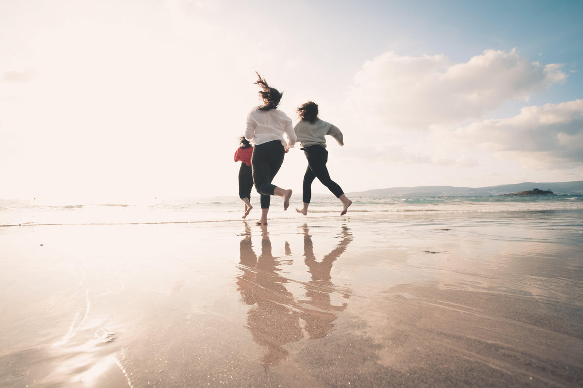 Three people running together towards the water