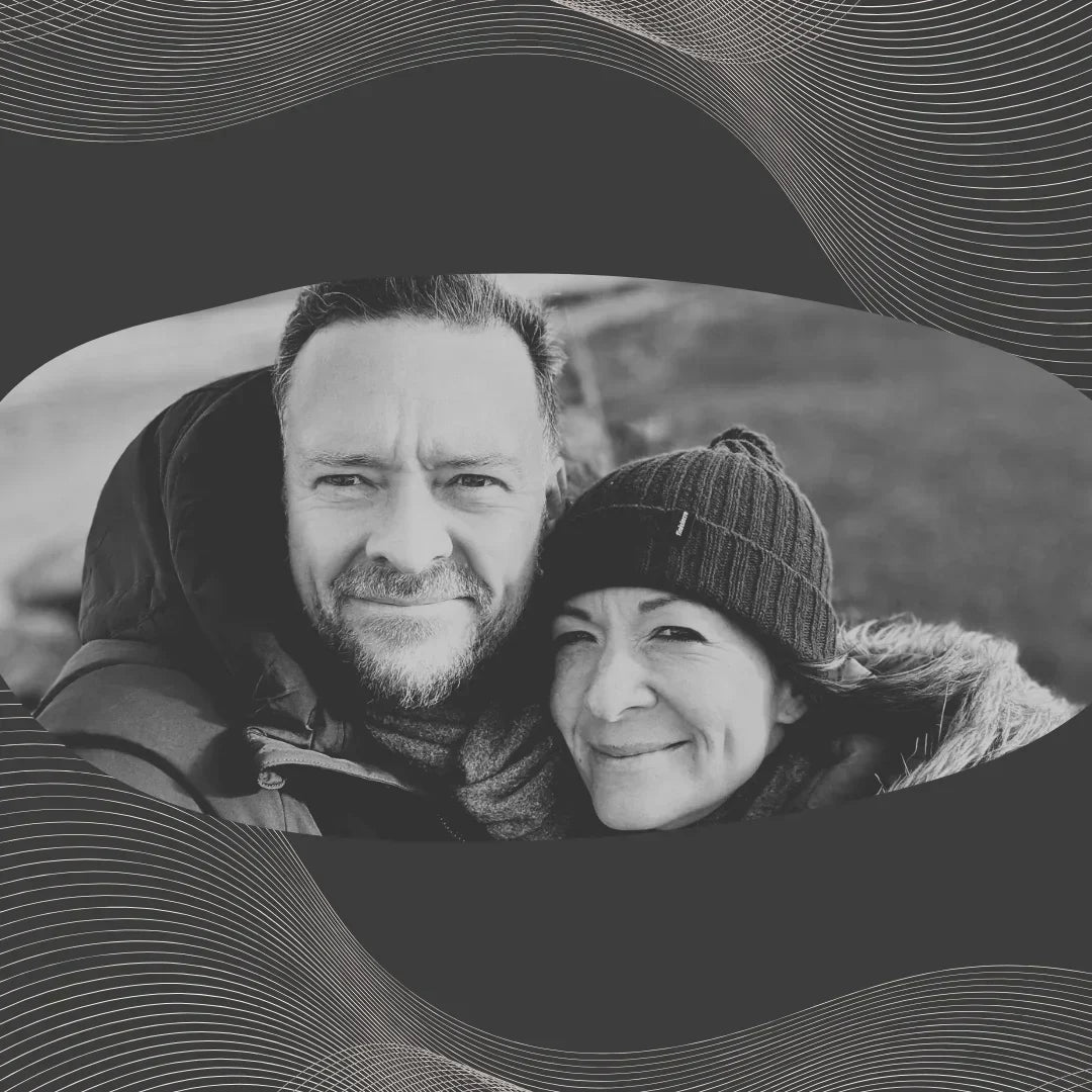 Smiling couple in winter jackets outdoors, black and white portrait on wavy abstract background