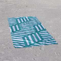 Green and white geometric beach towel on sandy beach