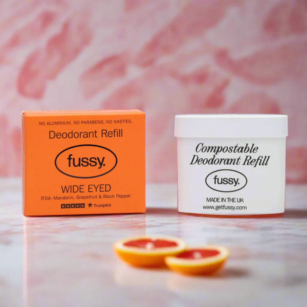 Fussy deodorant refill box and compostable refill tub on marble surface with grapefruit slices