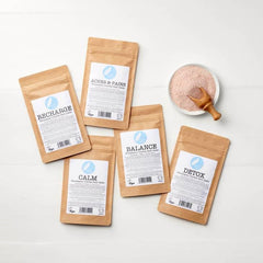Himalayan crystal bath salts pouches labeled Recharge, Calm, Balance, Detox, Aches &amp; Pains with pink salt bowl