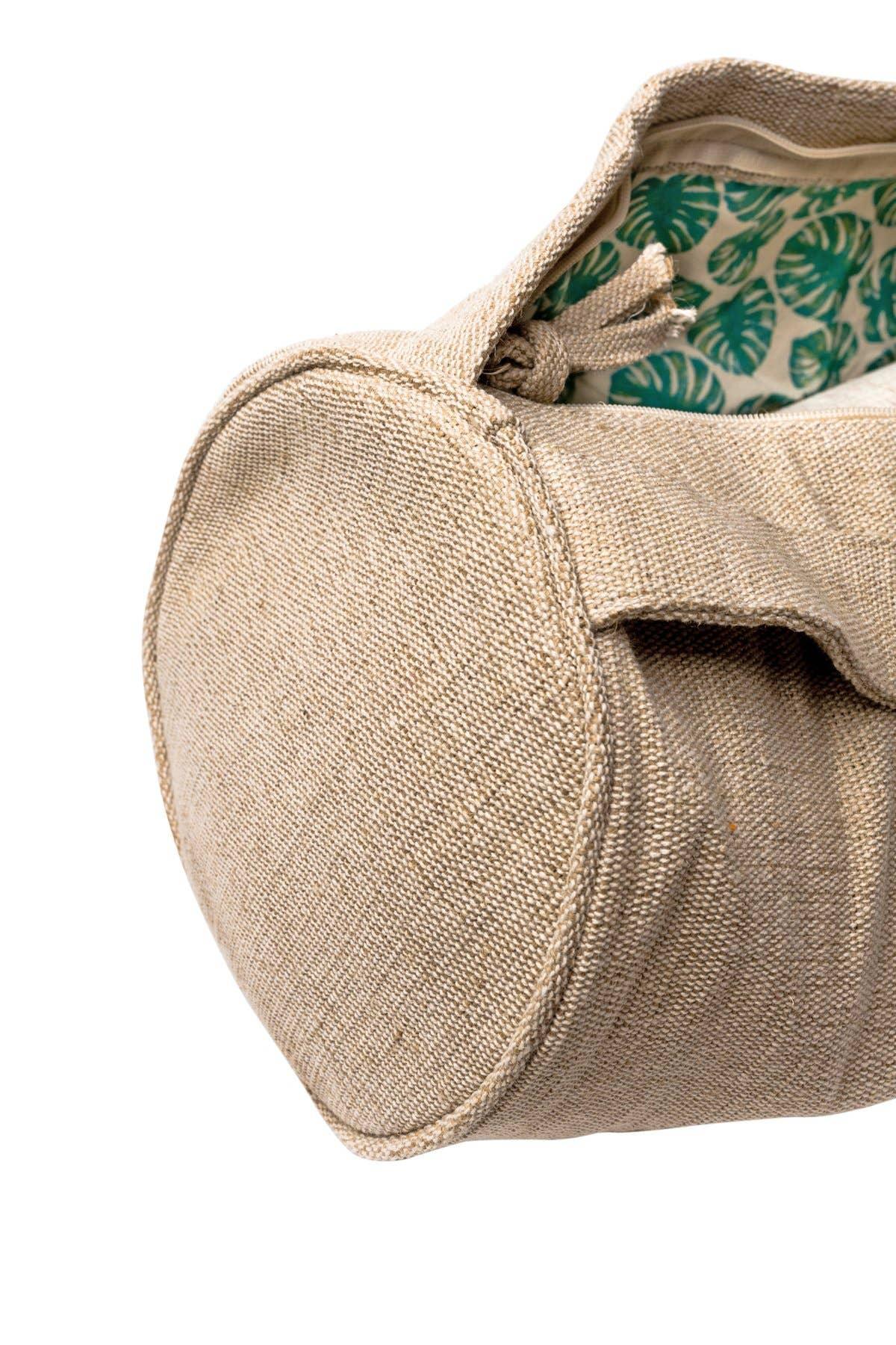 Beige jute duffel bag with green leaf print fabric lining and zip closure