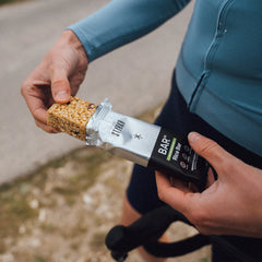 Cyclist opening a Styrkr rice bar energy snack outdoors