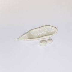 Creamy lotion swatch and drops on a white background, skincare product texture