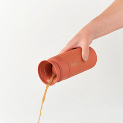 Hand pouring coffee from Sahara Red Brew 350ml insulated travel mug