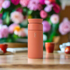 Sahara Red Brew 350ml insulated bottle on wooden table with blurred floral background