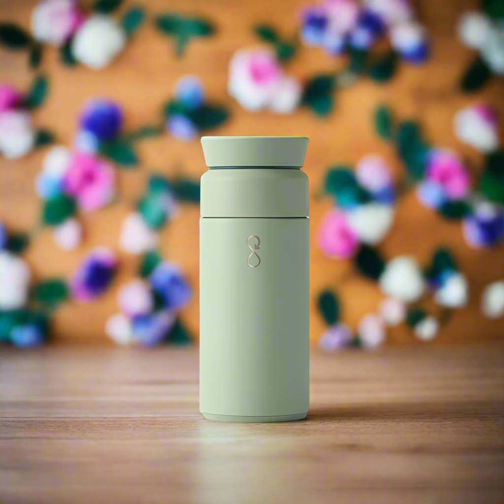 Shale green 350ml insulated tumbler on wooden surface with blurred floral background