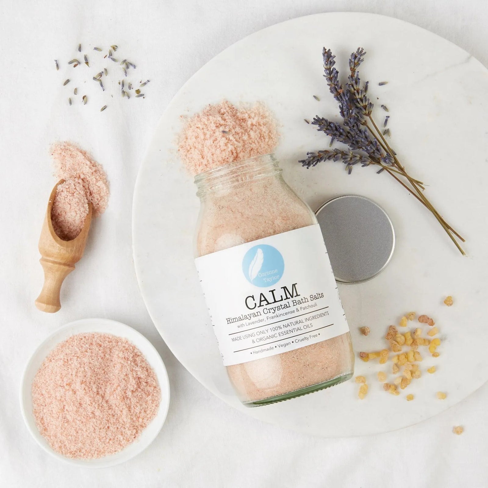 Calm Himalayan crystal bath salts jar with lavender, scoop, and natural ingredients on white background