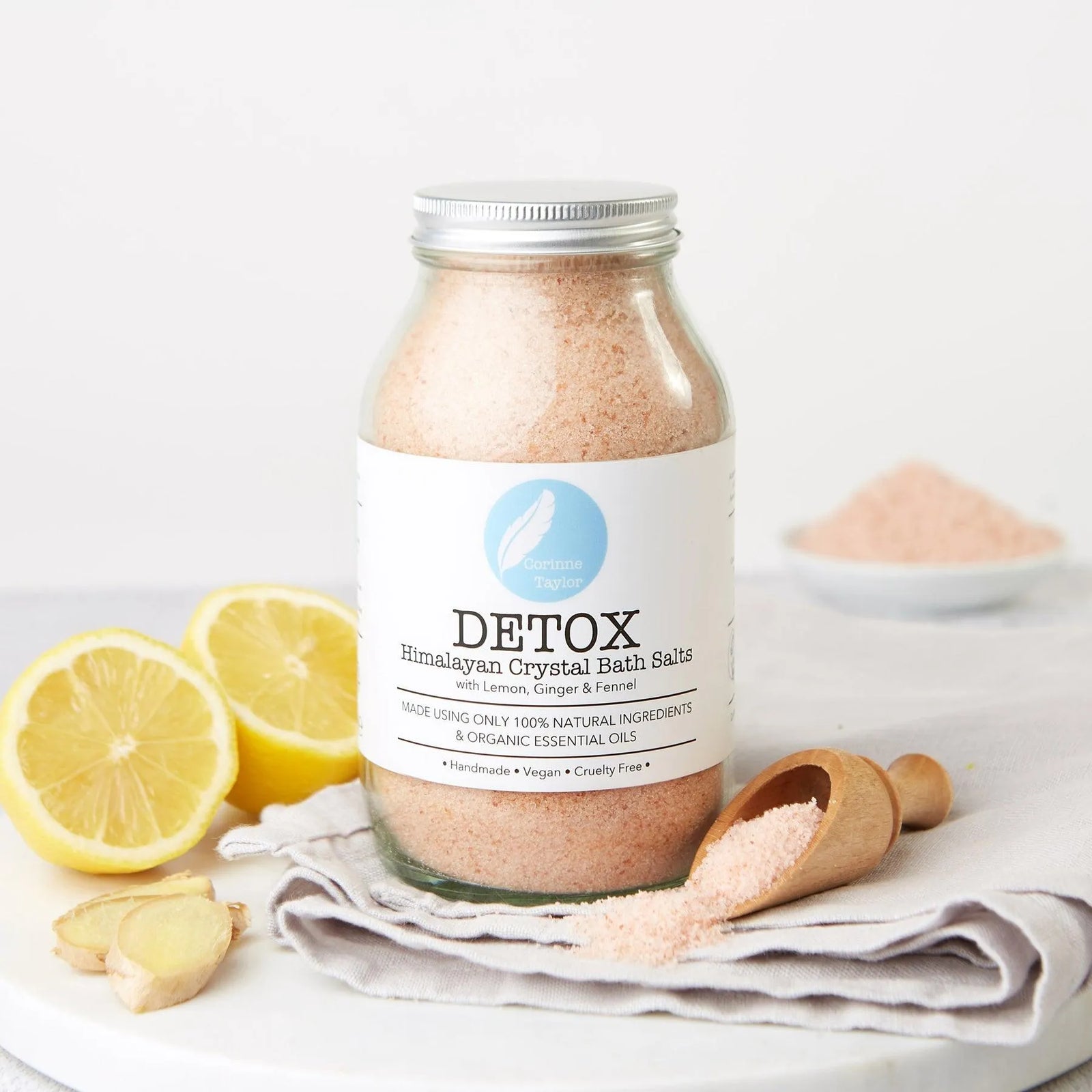 Detox Himalayan crystal bath salts jar with lemon slices, ginger, and wooden scoop.
