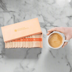 London Nootropics coffee sachets box and a hand holding a cup of coffee on marble surface