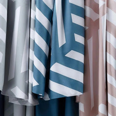 Striped beach towels in blue, gray, and beige hanging side by side