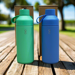 Green and blue reusable water bottles outdoors on a wooden table, eco-friendly packaging