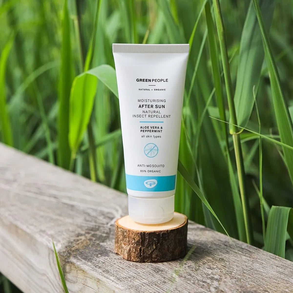 Green People moisturising after sun insect repellent tube on wood with grass background
