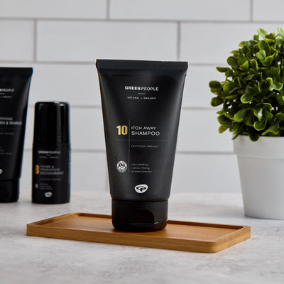 Green People Itch Away Shampoo on bamboo tray, deodorant, plant, white tile background