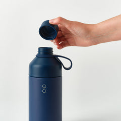 Hand opening navy blue reusable water bottle on white background