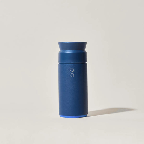 Blue reusable insulated travel mug with minimalist infinity logo on light background