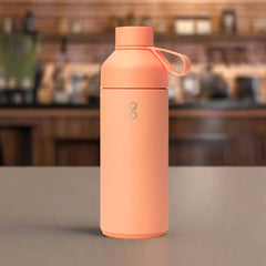 Sunset peach reusable water bottle with loop lid on cafe counter
