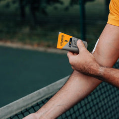 Man applying LifeJacket SPF30 Sun Gel on arm by outdoor tennis court