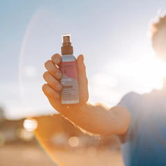 Hand holding LifeJacket SPF 50 sun protection spray outdoors in bright sunlight