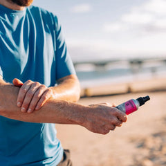 Man applying SPF 50 sun protection spray on arm at the beach
