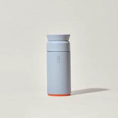 Matte grey insulated travel mug with orange base on light background