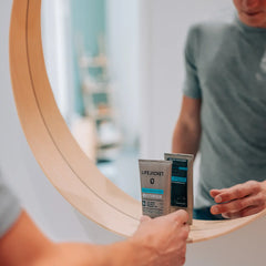 Man holding LifeJacket SPF 30 Daily Protection Moisturiser in front of bathroom mirror