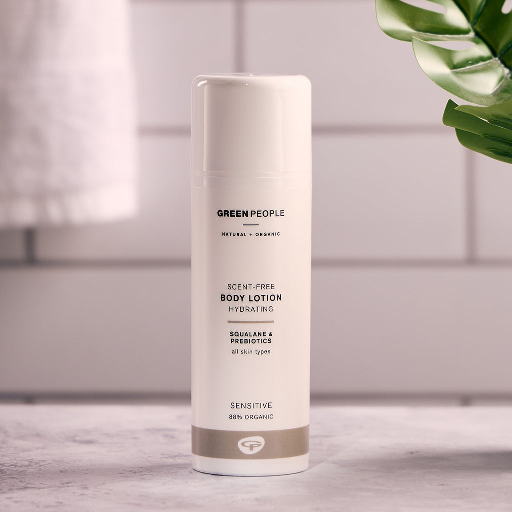 Green People scent-free body lotion bottle on bathroom counter with tile background