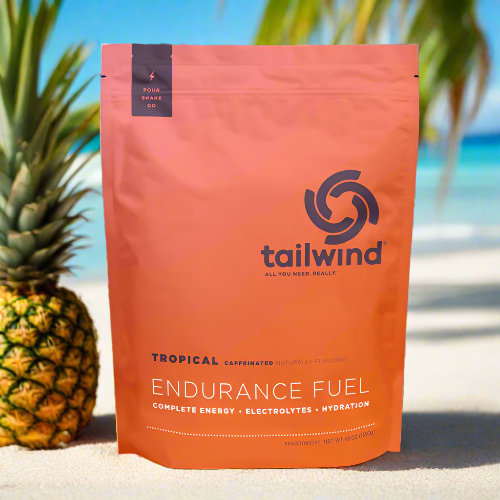 Tailwind Endurance Fuel Tropical flavor drink mix on sandy beach with pineapple