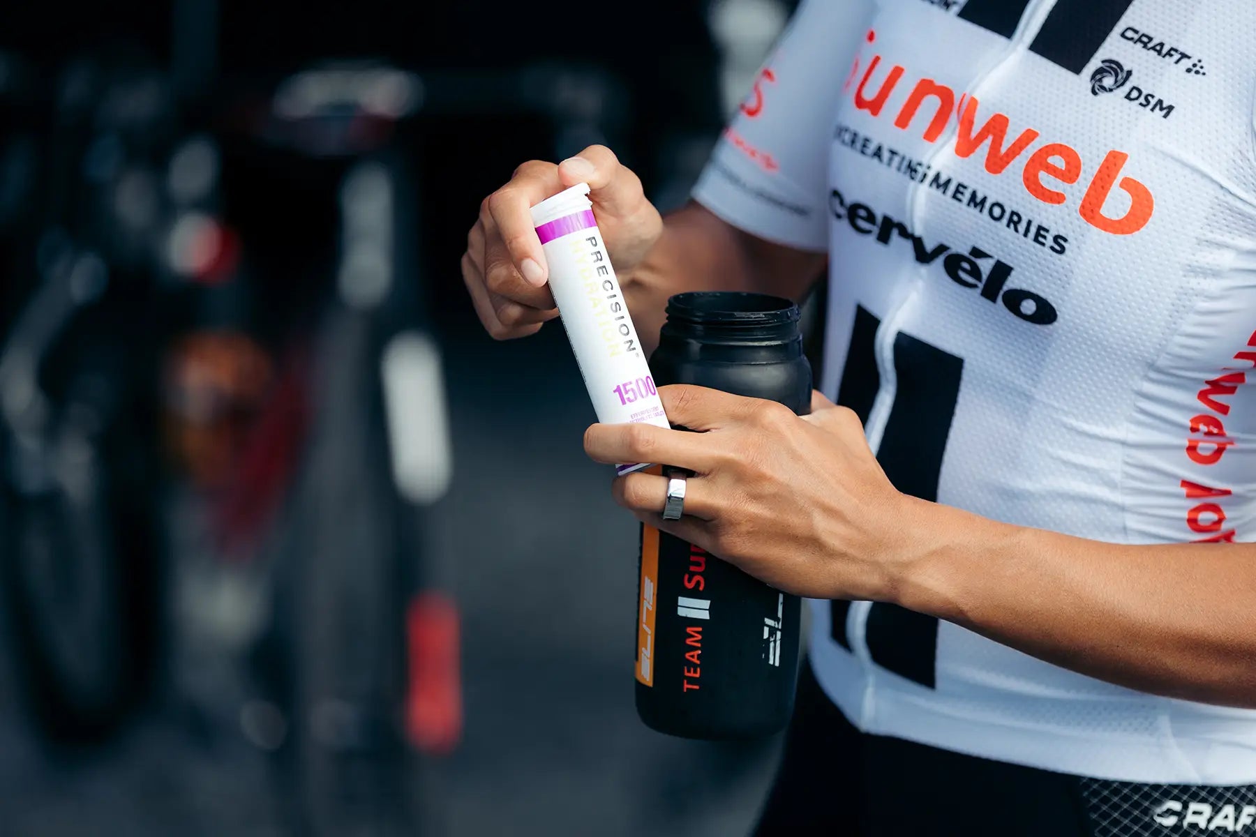 Person holding a supplement container with a blurred bike in the background