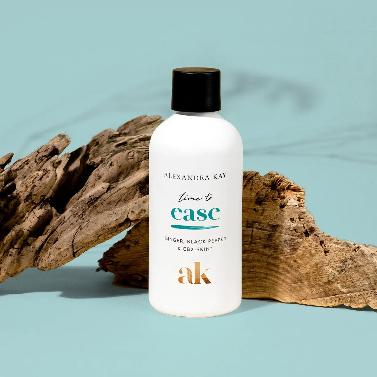 Alexandra Kay Time to Ease oil bottle with black cap on wood against blue background