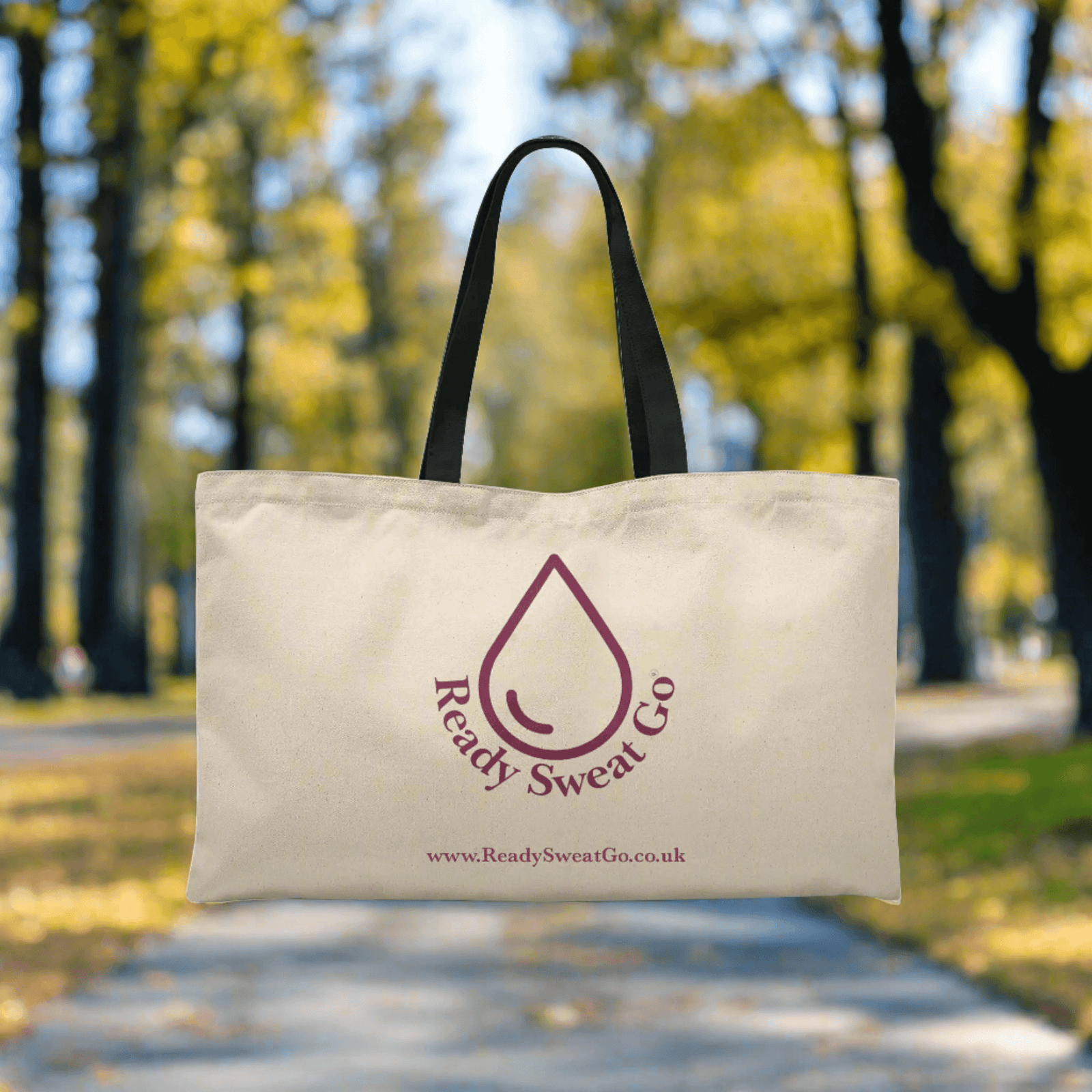 Ready Sweat Go canvas tote bag with black handles outdoors on a tree-lined path