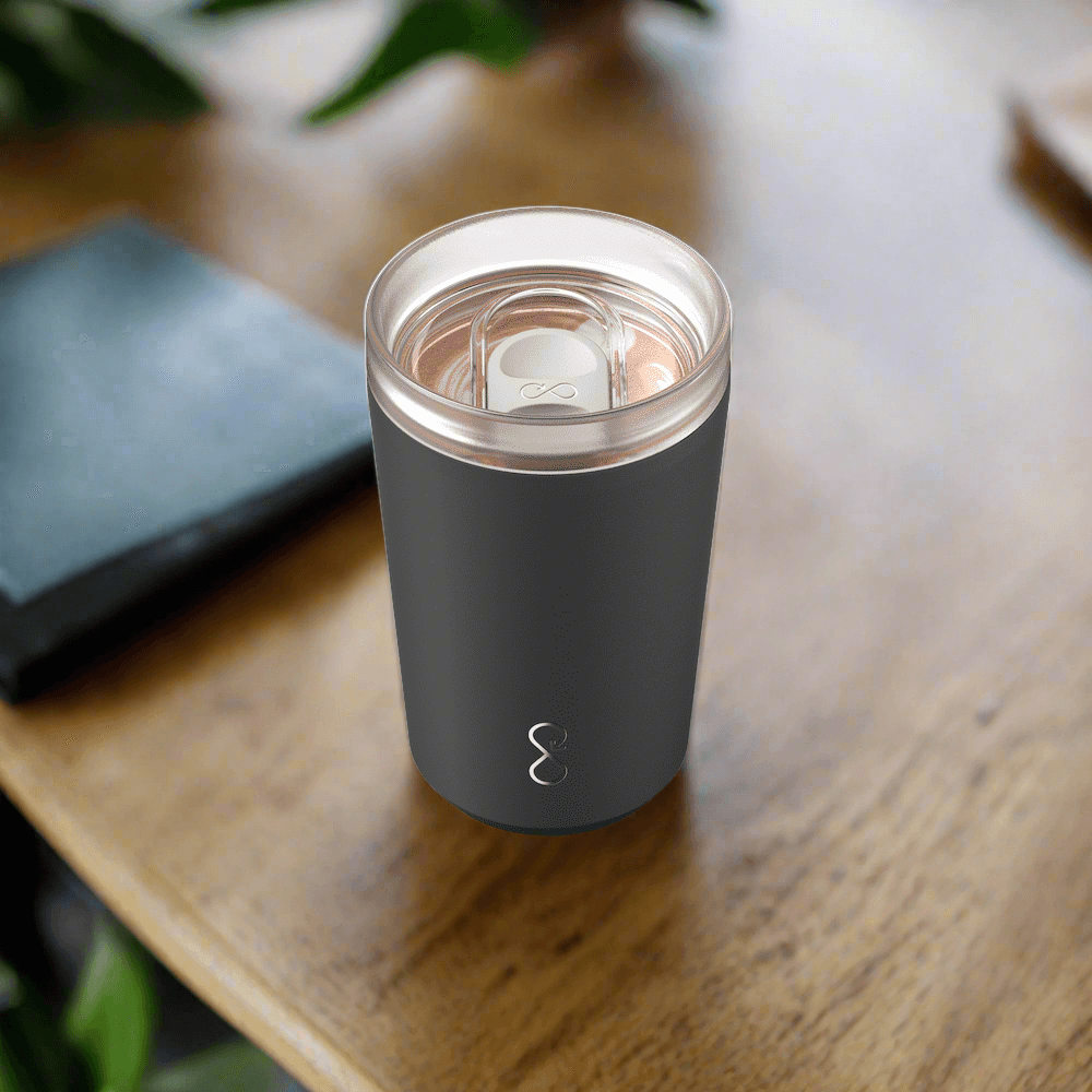 Matte black insulated tumbler with transparent lid on wooden table, modern minimalist design