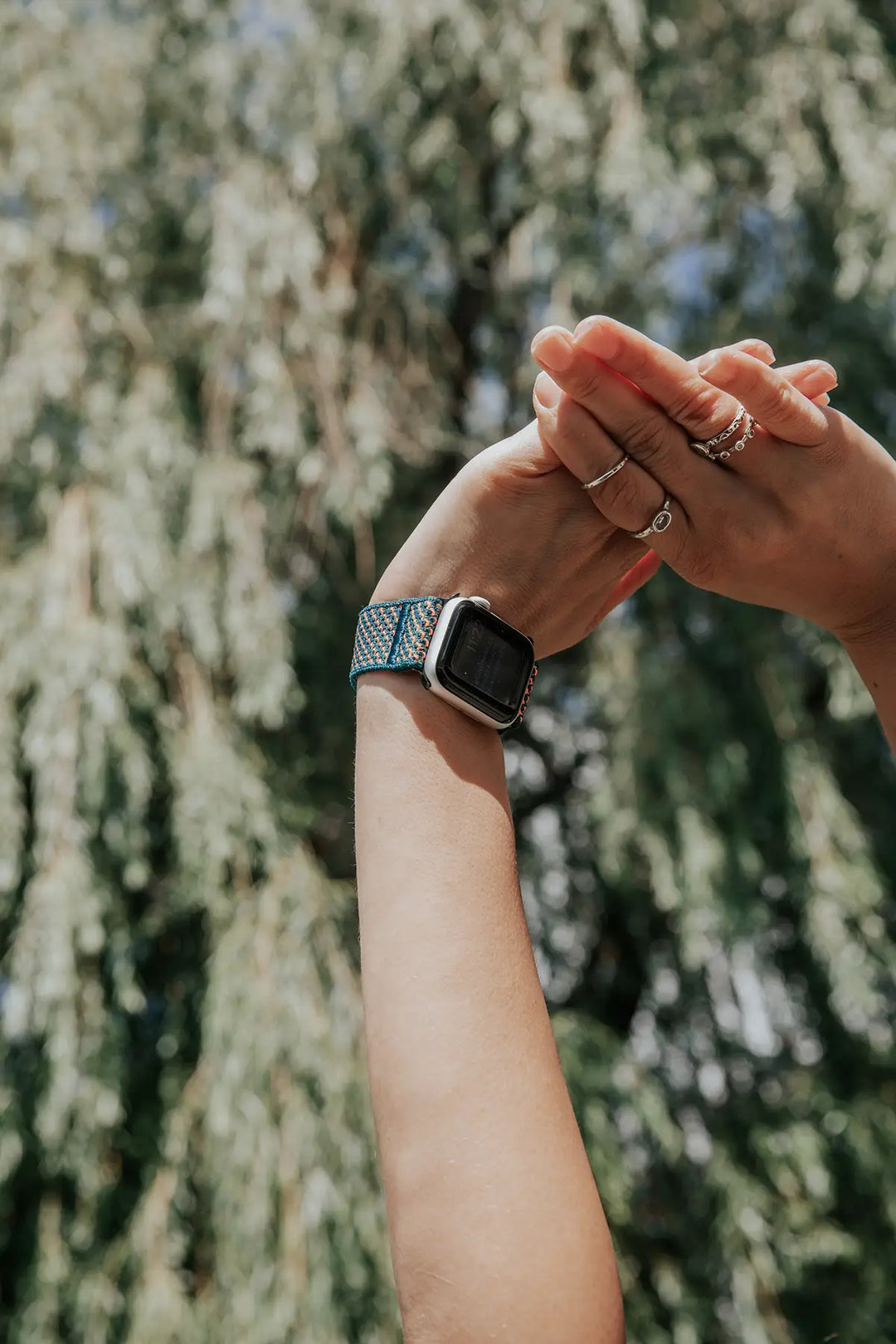 arms reach up into sunshine with a smart watch on