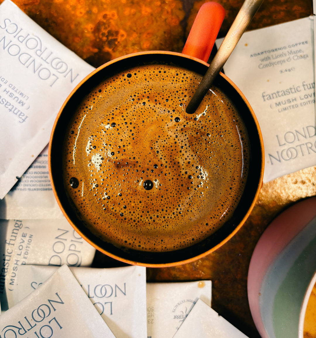 Coffee mug surrounded by London Nootropics Mush Love sachets