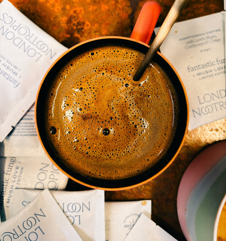 Coffee mug surrounded by London Nootropics Mush Love sachets