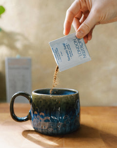 Pouring a London Nootropics Mush Love sachet into a ceramic mug