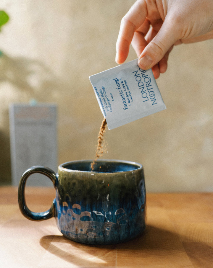 Pouring a London Nootropics Mush Love sachet into a ceramic mug