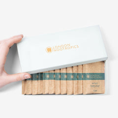 Hand opening London Nootropics Mojo coffee sachets box on white background
