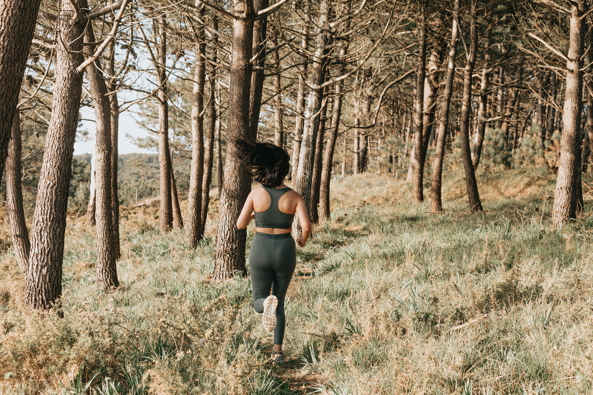 Runner moving along a narrow forest trail in changing outdoor conditions