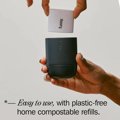 Hand holding fussy deodorant case with compostable refill, eco-friendly packaging visible.