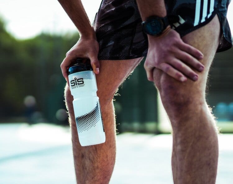 Athlete holding a Science in Sport bottle during outdoor training