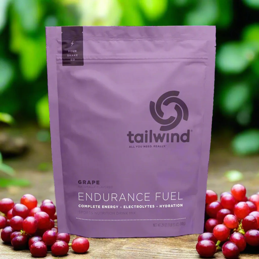 Tailwind Endurance Fuel grape flavor sports nutrition drink mix pouch with fresh grapes outdoors