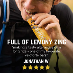 Cyclist eating Veloforte Zenzero energy bar outdoors, product packaging visible, review text overlay