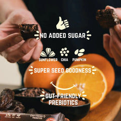 Hands holding Veloforte orange cacao bar with orange slices, dates, and seed ingredients