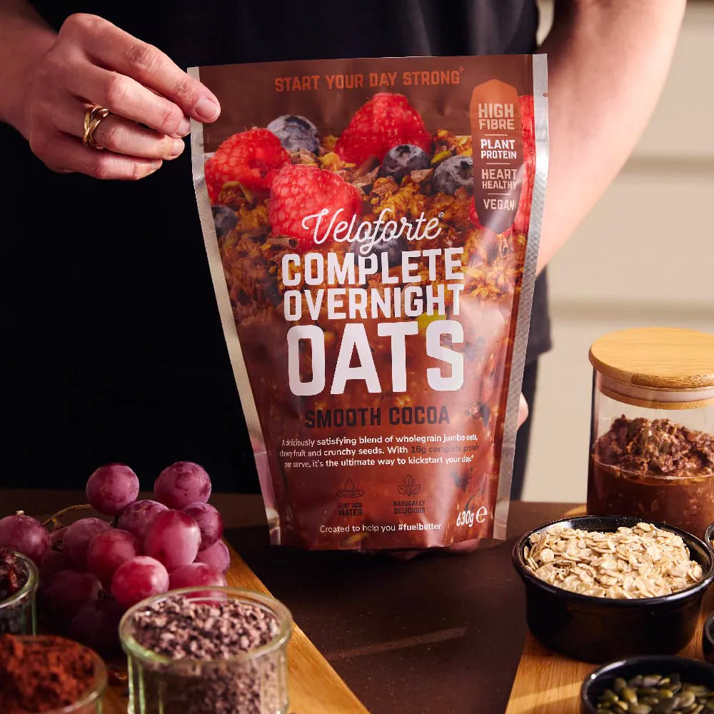 Veloforte Complete Overnight Oats Smooth Cocoa pouch on kitchen counter with oats, grapes, and seeds