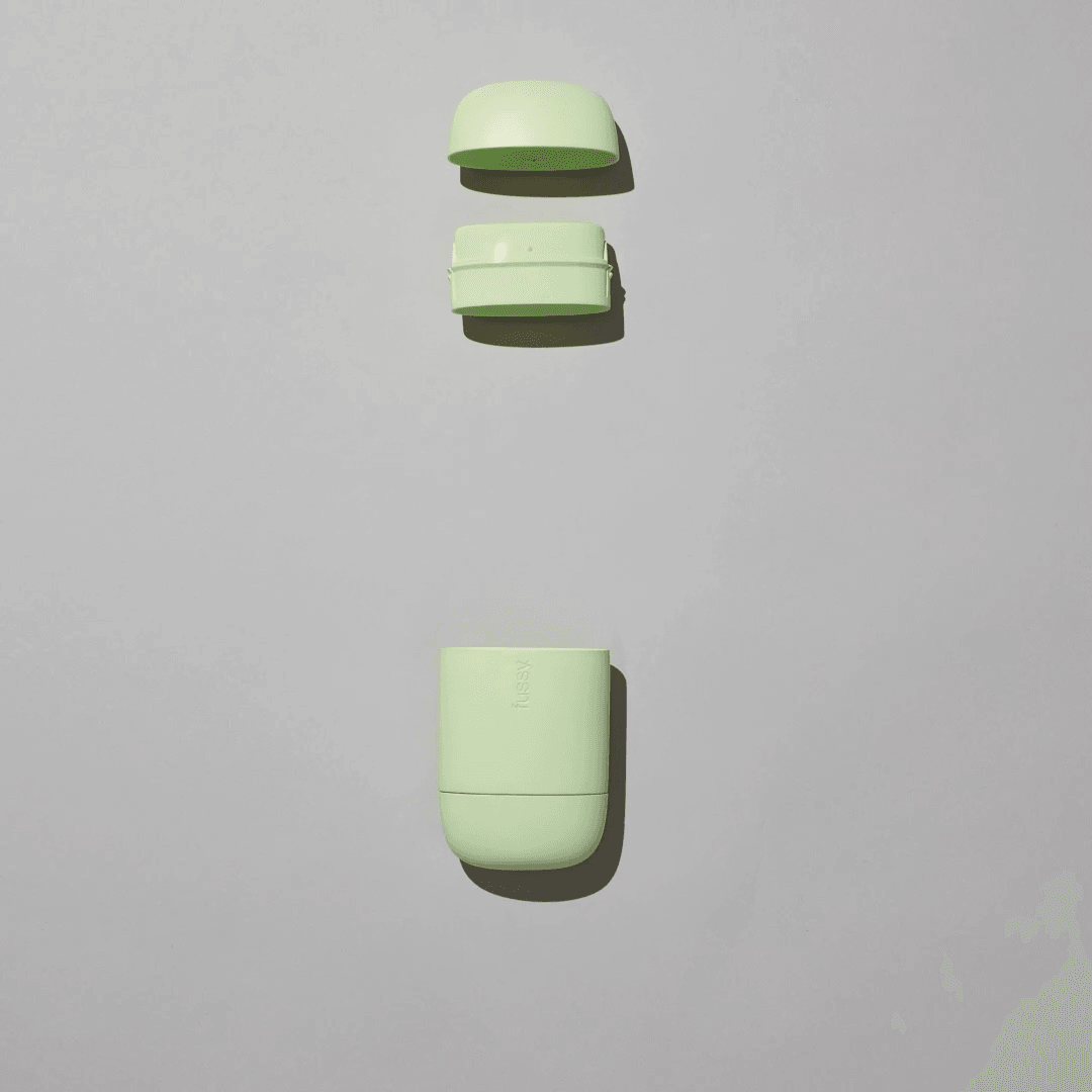 Light green reusable deodorant case in three parts on a plain light background