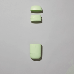 Light green reusable deodorant case in three parts on a plain light background